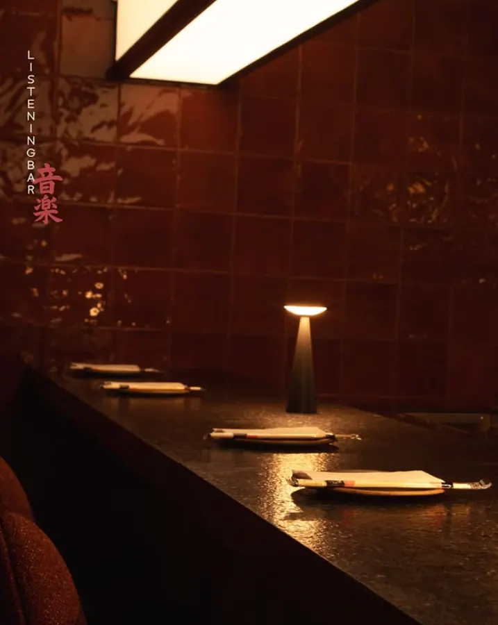 Balcão do Kobi Izakaya com iluminação quente e garrafas ao fundo